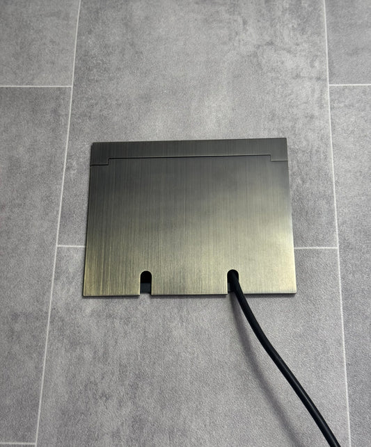 Double Antique Brass Recessed Floor Socket With Lid Closed Flat Showing Just Cable Coming Out If The Socket - Front On View.