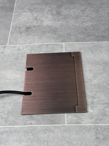 Double Antique Copper Recessed Floor Socket With Lid Closed Flat Showing Just Cable Coming Out If The Socket - Side On View.