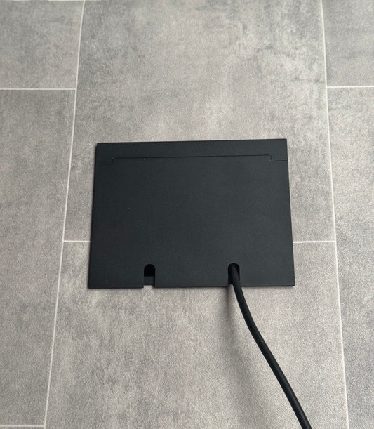 Double Matt Black Recessed Floor Socket With Lid Closed Flat Showing Just Cable Coming Out If The Socket - Front On View