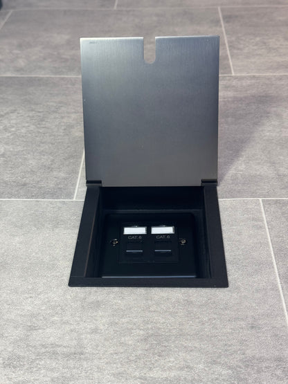 An old bronze recessed floor socket with a cover, showing a 2 gang Cat6 RJ45 socket beneath.
