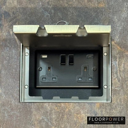 Antique Brass Double Recessed Flush Floor Socket with USB A + C Plug Socket n a stone floor.