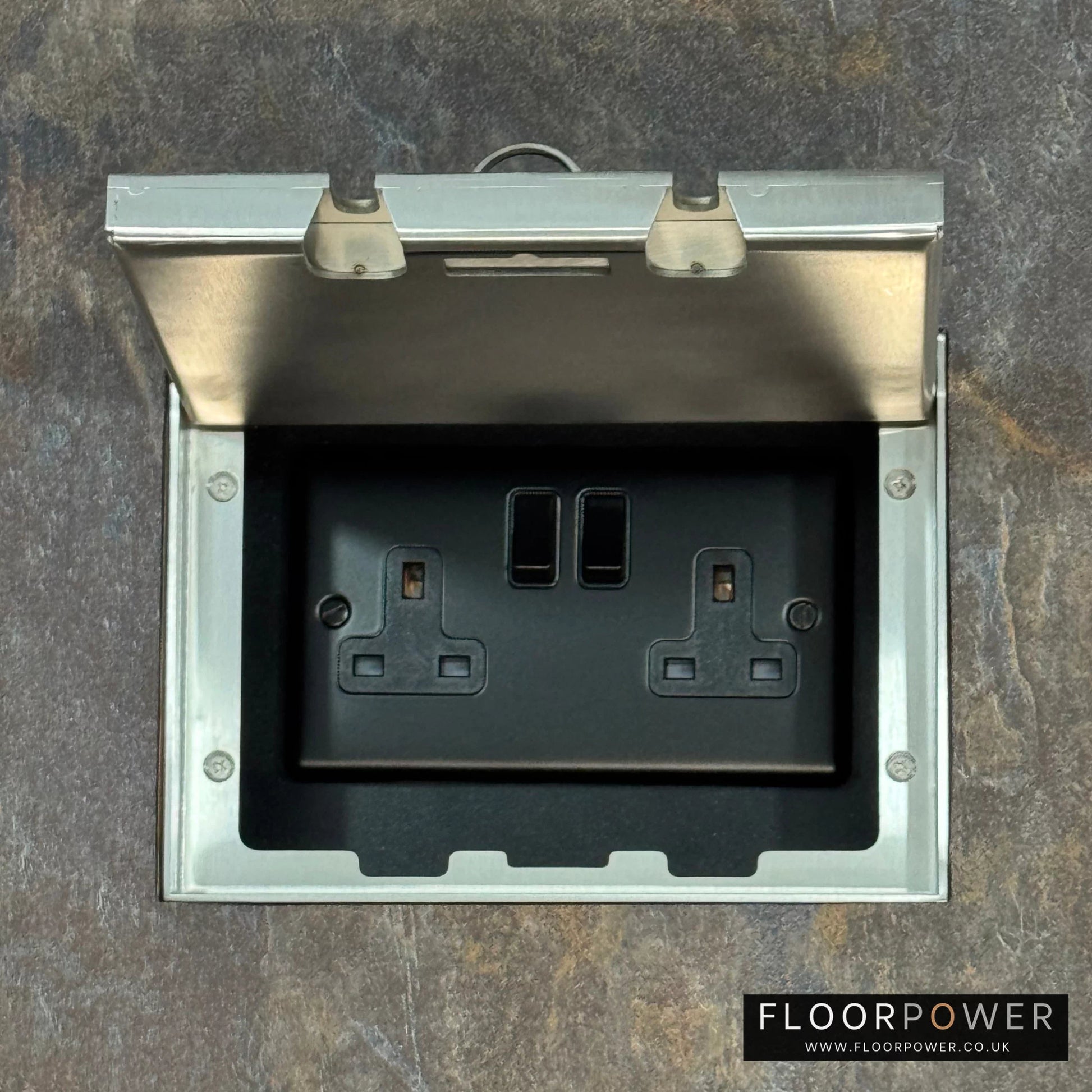 Satin Stainless Double Recessed Flush Floor Socket with 13A Switched Plug Socket n a stone floor.