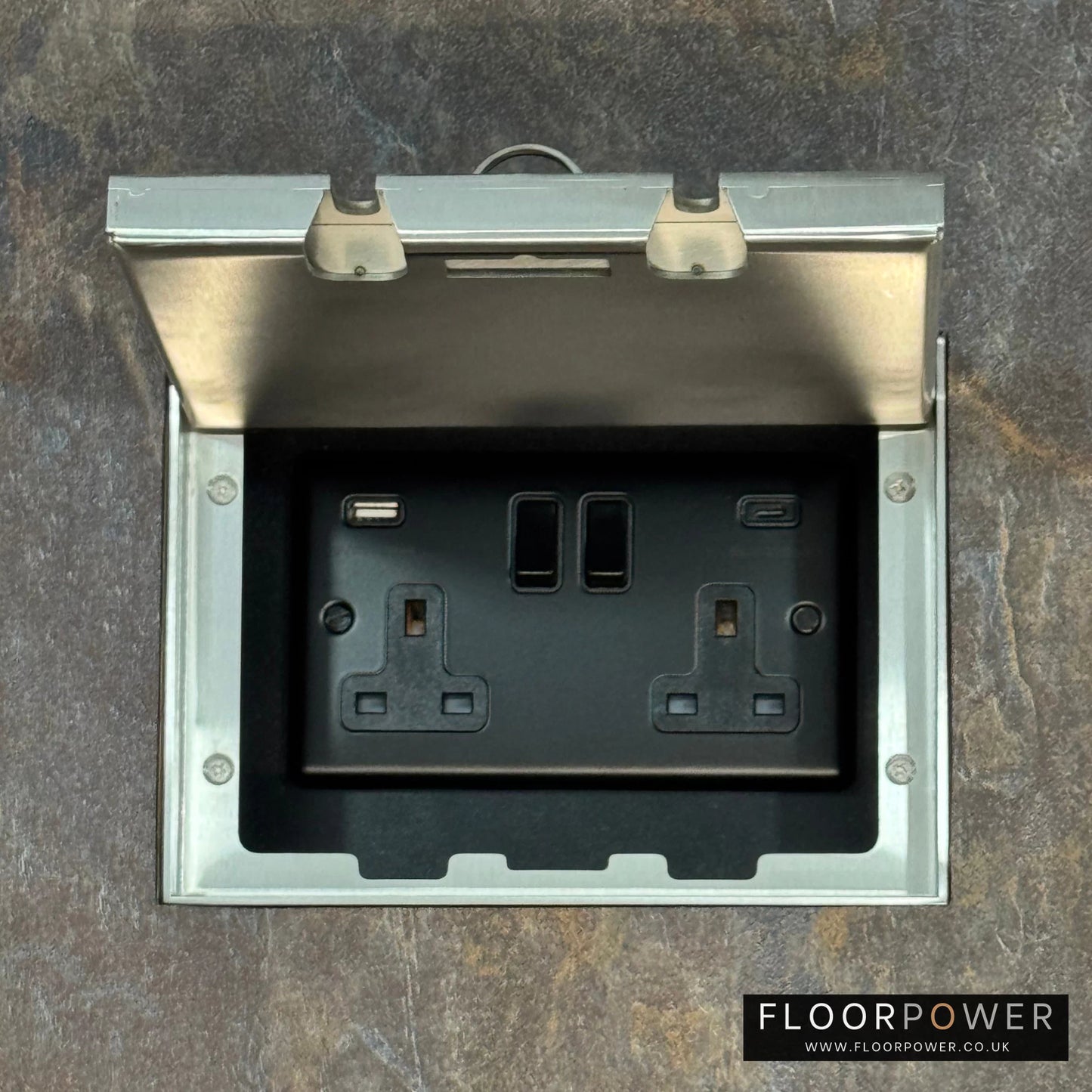 Satin Stainless Double Recessed Flush Floor Socket with USB A + C Plug Socket n a stone floor.
