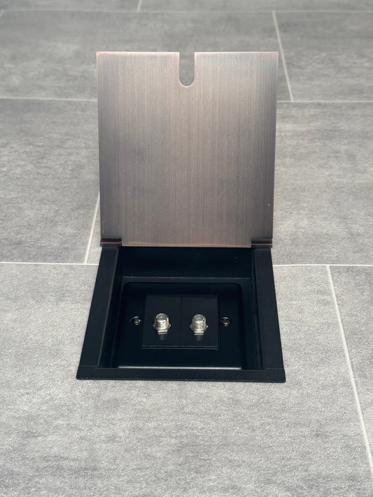 Recessed floor socket with antique copper finish, consisting of a single gang box and a 2 gang satellite socket, installed in a tiled floor.