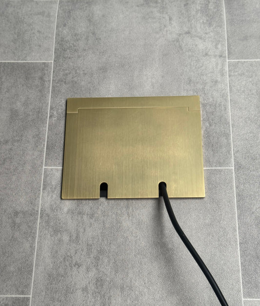 Double Satin Brass Recessed Floor Socket With Lid Closed Flat Showing Just Cable Coming Out If The Socket - Front On View.