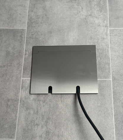 Double Satin Stainless Recessed Floor Socket With Lid Closed Flat Showing Just Cable Coming Out If The Socket - Front On View.