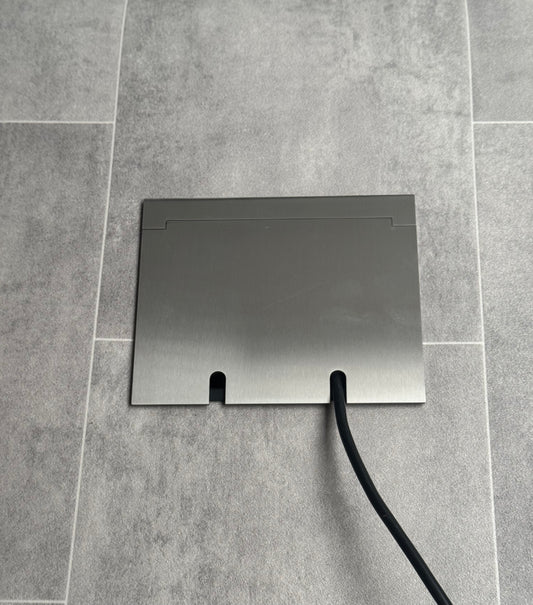 Double Satin Stainless Recessed Floor Socket With Lid Closed Flat Showing Just Cable Coming Out If The Socket - Front On View.