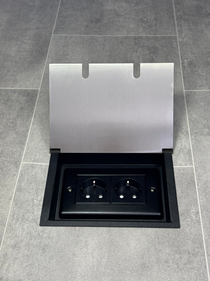 A satin stainless steel double recessed floor socket with two 13amp unswitched Schuko plug sockets, on a tiled floor.
