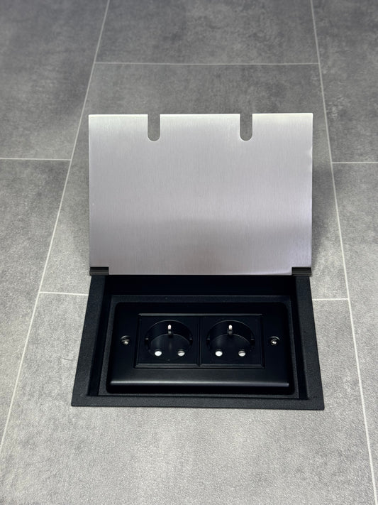 A satin stainless steel double recessed floor socket with two 13amp unswitched Schuko plug sockets, on a tiled floor.