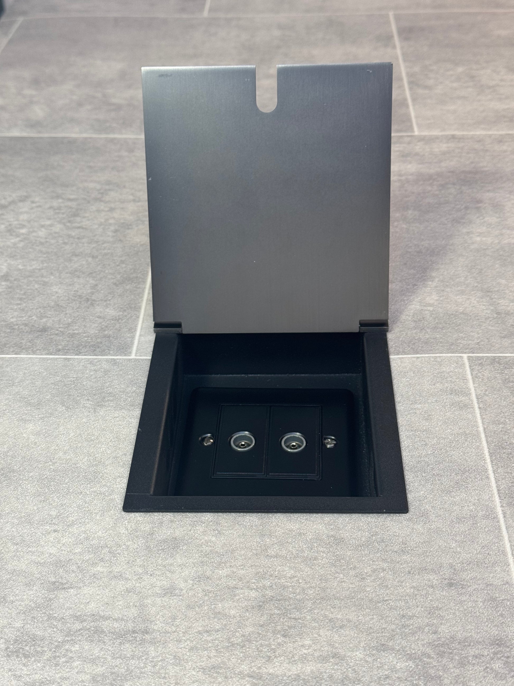 Old bronze recessed floor socket with a 2 gang TV socket, shown in an open position with the surrounding floor visible.
