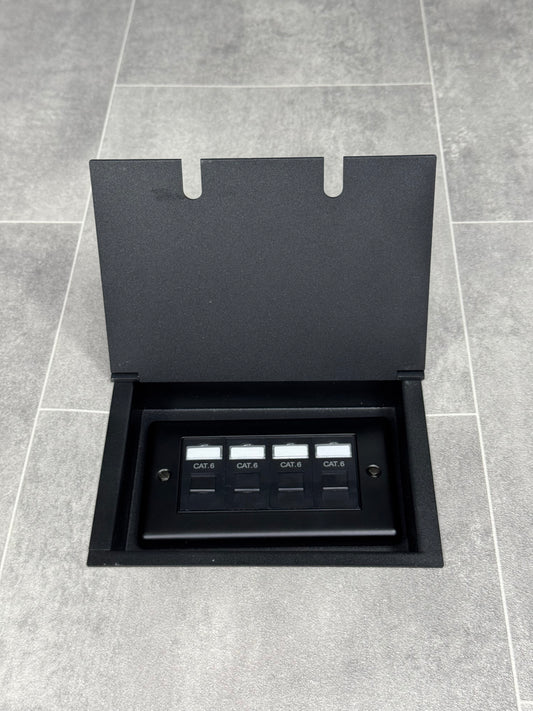 A matt black double recessed floor socket with a black base installed on a grey floor, opened to show the 4 gang RJ45 cat6 socket.