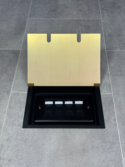 A satin brass double recessed floor socket with a black base installed on a grey floor, opened to show the 4 gang RJ45 cat6 socket.