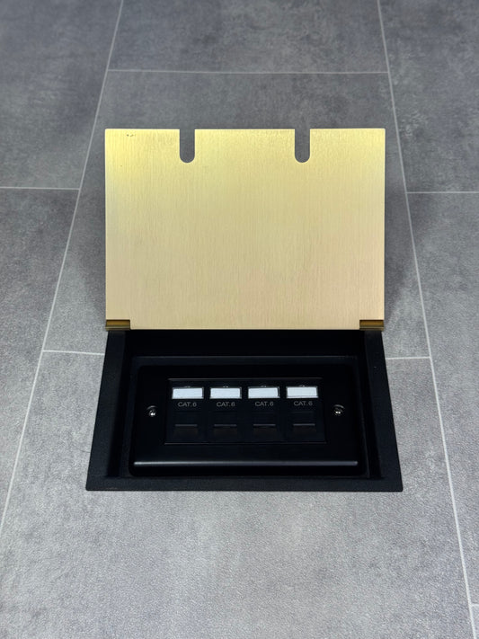A satin brass double recessed floor socket with a black base installed on a grey floor, opened to show the 4 gang RJ45 cat6 socket.