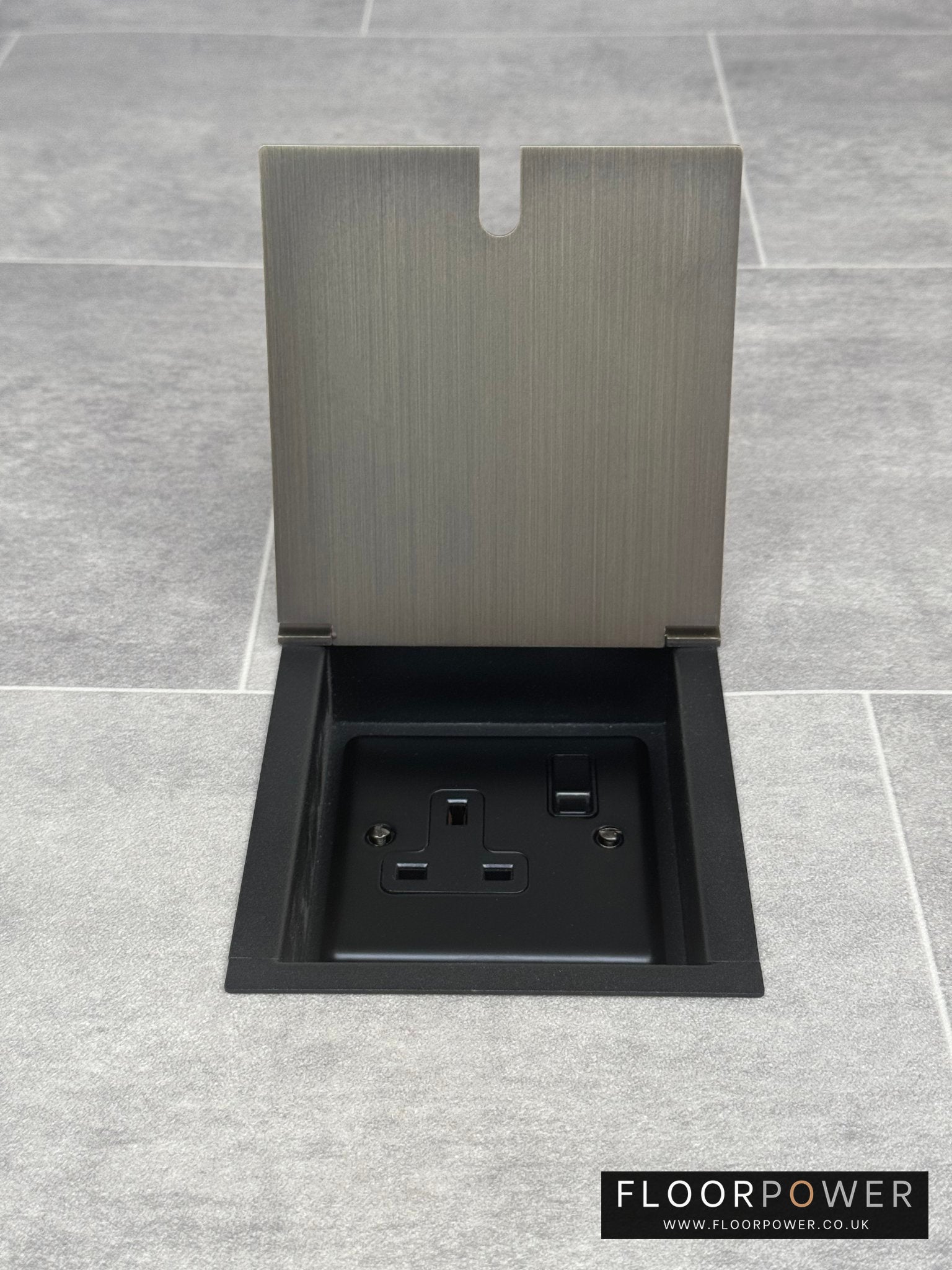 A recessed floor socket with a cover, in antique brass finish, opened to show the 13 Amp socket.