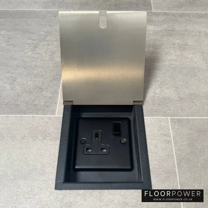 A recessed floor socket with a cover, in satin nickel finish, opened to show the 13 amp socket.