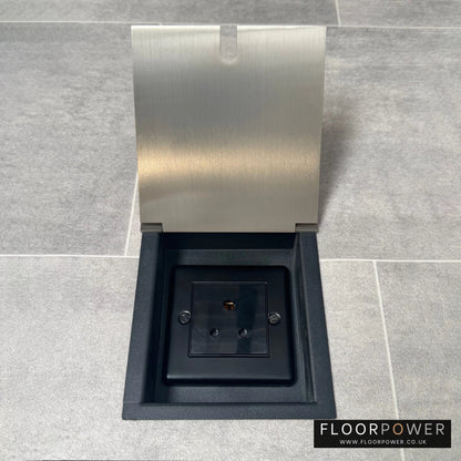 A 5 amp round pin recessed floor socket for lighting with satin nickel finish cover, set against a grey tiled floor.