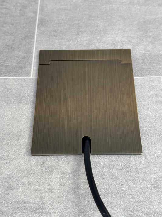 Single Antique Brass Recessed Floor Socket With Lid Closed Flat Showing Just Cable Coming Out If The Socket - Front On View.