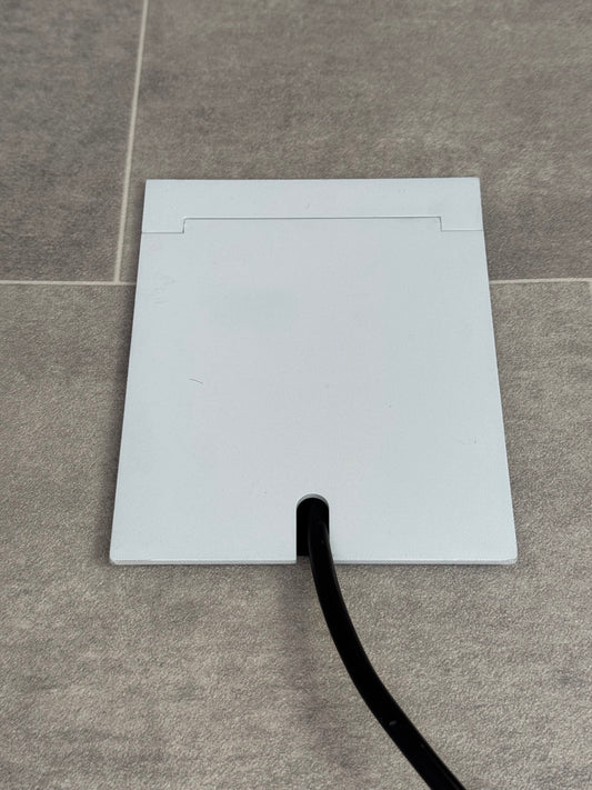 Single Matt White Recessed Floor Socket With Lid Closed Flat Showing Just Cable Coming Out If The Socket - Front On View.
