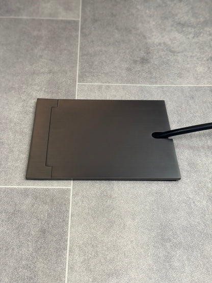 Single Old Bronze Recessed Floor Socket With Lid Closed Flat Showing Just Cable Coming Out If The Socket - Side On View.
