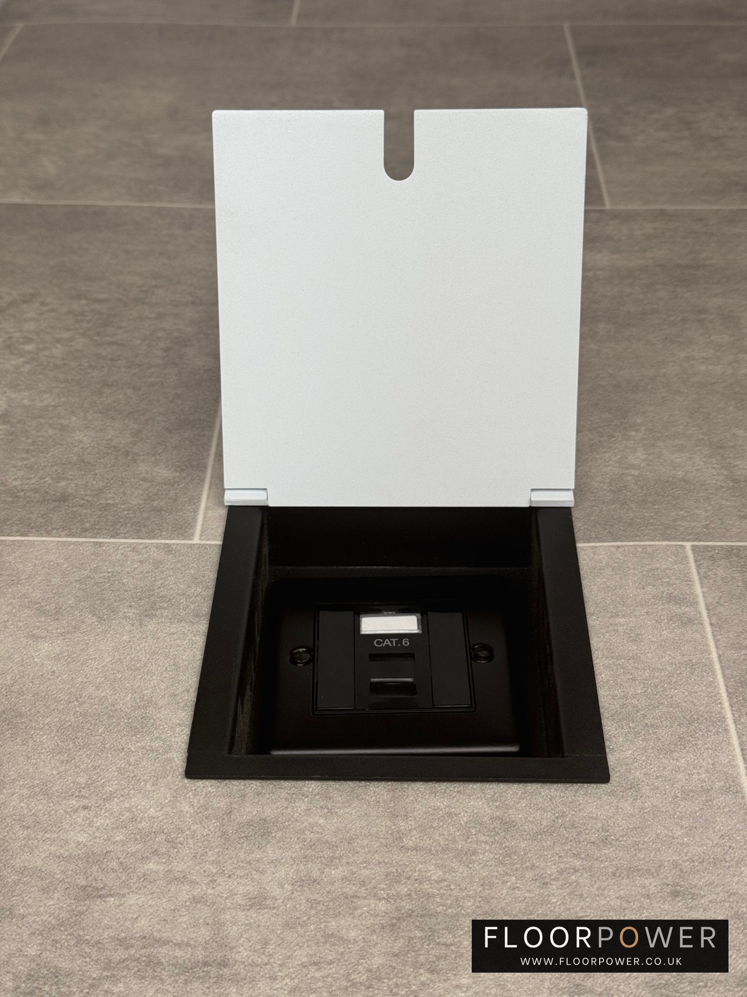 A white recessed floor socket with a black base, opened to reveal the Cat6 RJ45 socket.
