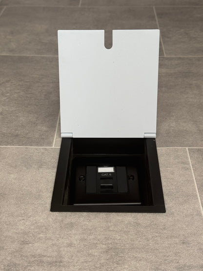 A white recessed floor socket with a black base, opened to reveal the Cat6 RJ45 socket.