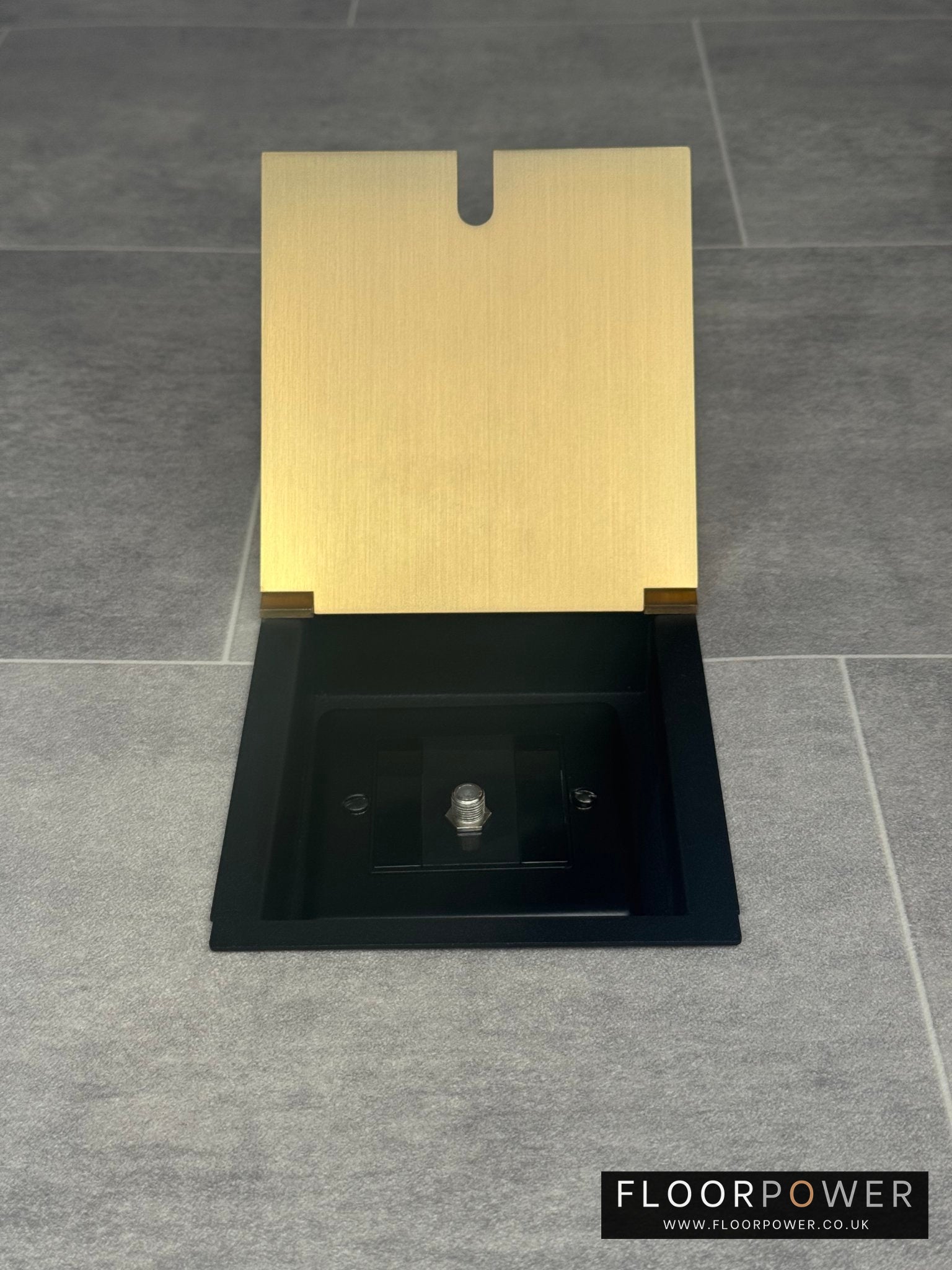 A satin brass recessed floor socket with a single satellite socket, installed on a grey floor.