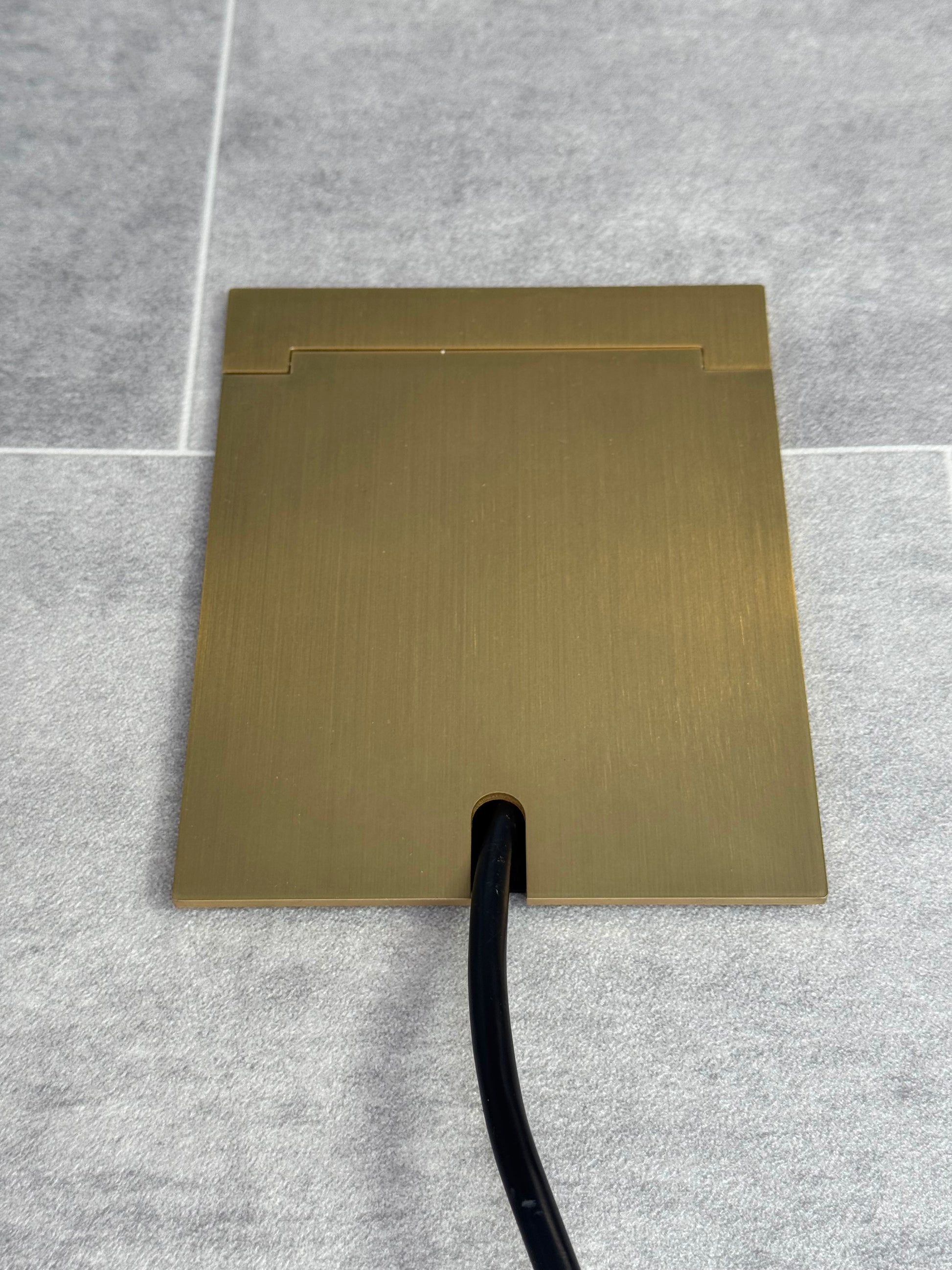 Single Satin Brass Recessed Floor Socket With Lid Closed Flat Showing Just Cable Coming Out If The Socket - Front On View.
