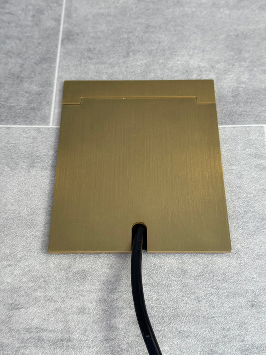 Single Satin Brass Recessed Floor Socket With Lid Closed Flat Showing Just Cable Coming Out If The Socket - Front On View.