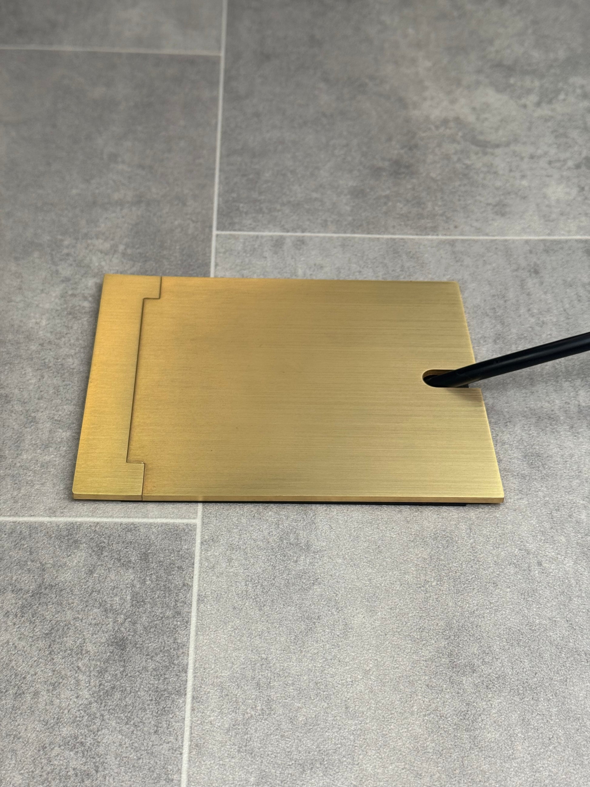 Single Satin Brass Recessed Floor Socket With Lid Closed Flat Showing Just Cable Coming Out If The Socket - Side On View.