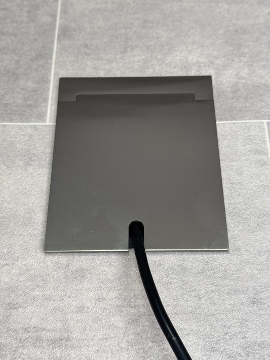 Single Satin Stainless Recessed Floor Socket With Lid Closed Flat Showing Just Cable Coming Out If The Socket - Front On View.