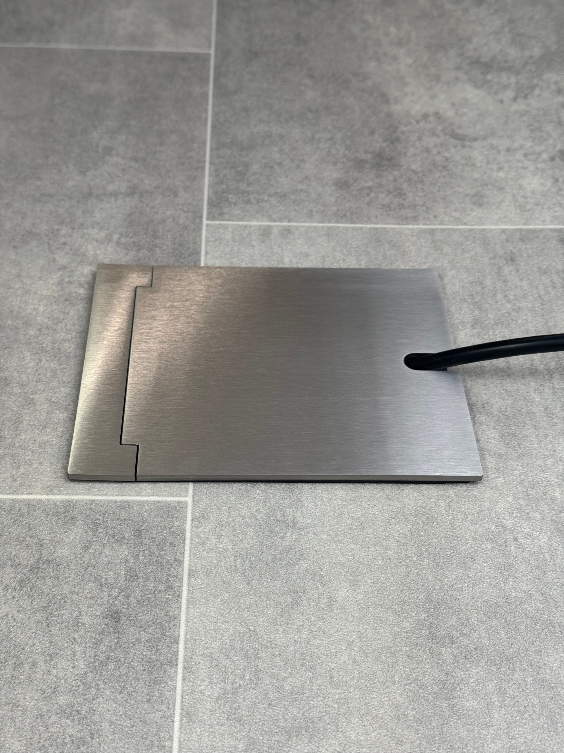 Single Satin Satinless Recessed Floor Socket With Lid Closed Flat Showing Just Cable Coming Out If The Socket - Side On View.