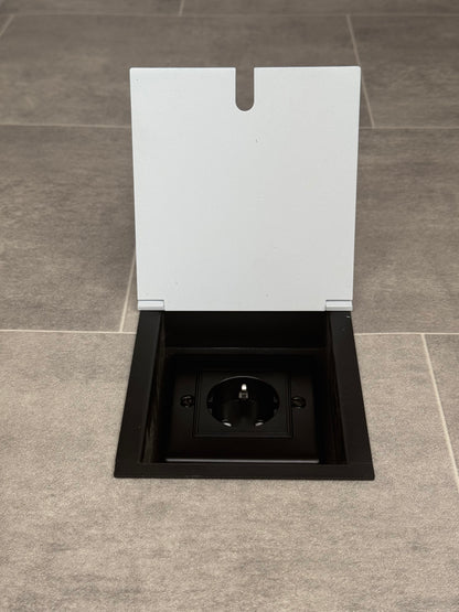 White recessed floor socket with a single Schuko (European) plug socket.