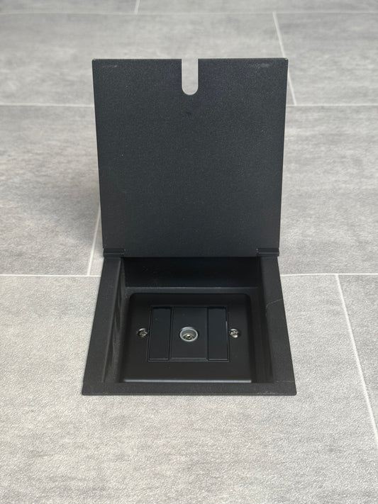 A matt black recessed floor socket designed for integrating a television socket into the floor, shown in an open position.