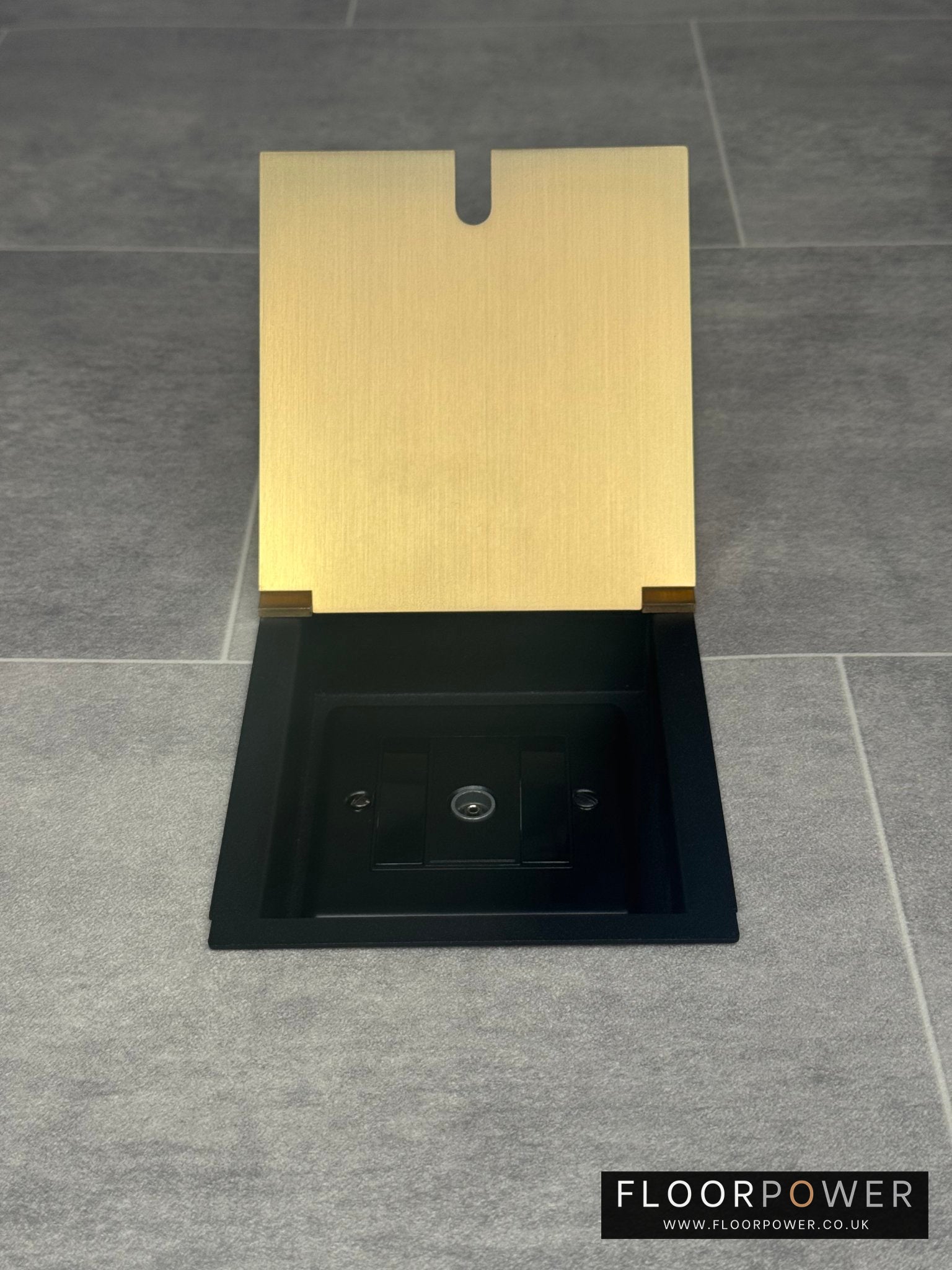 A satin brass recessed floor socket with a single 1 gang TV aerial socket, shown open,  installed in a floor.