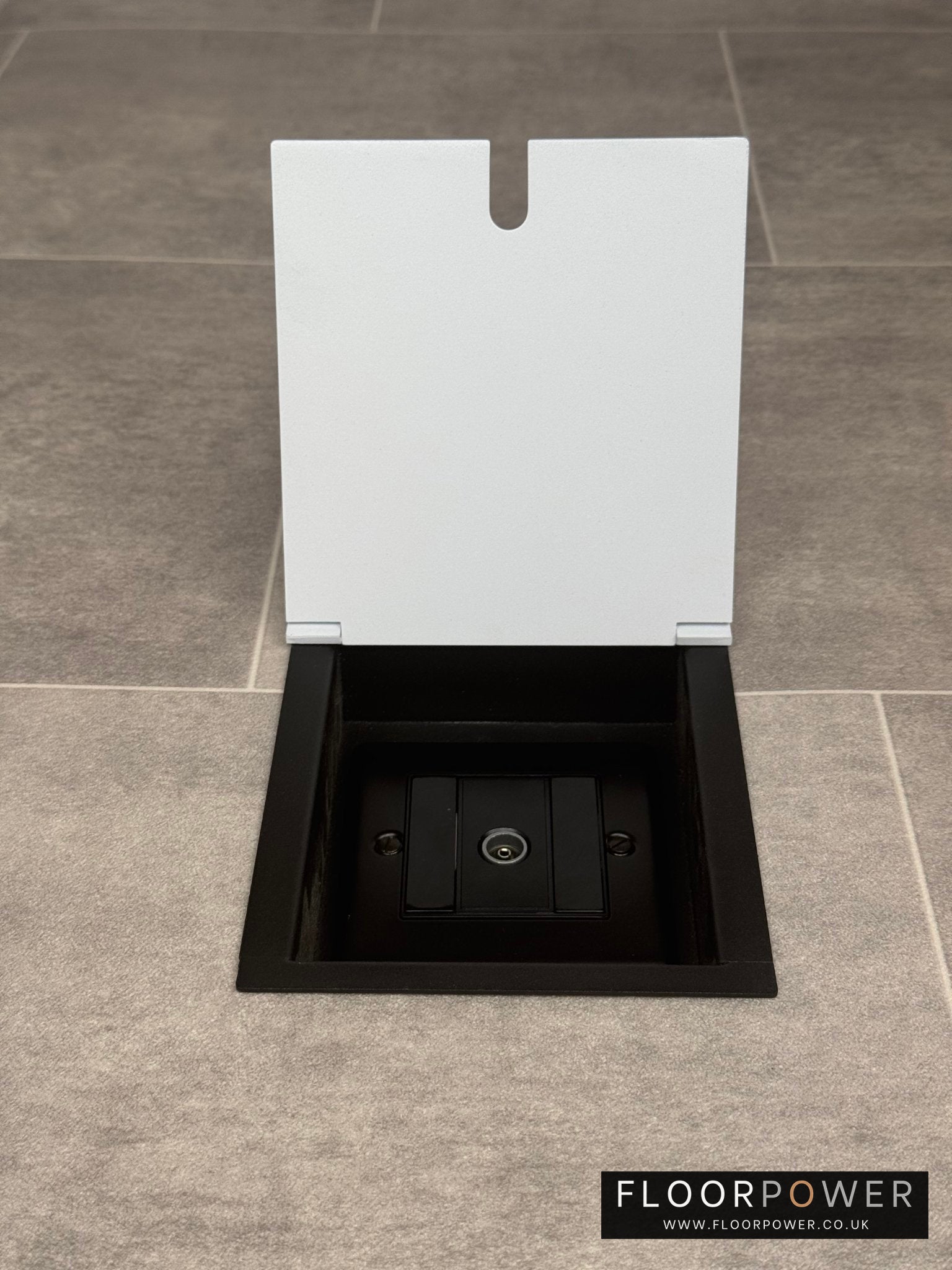 A recessed floor socket with a white lid and a single aerial (TV) socket.