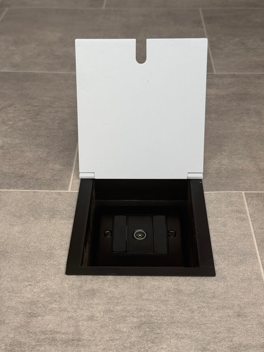 A recessed floor socket with a white lid and a single aerial (TV) socket.