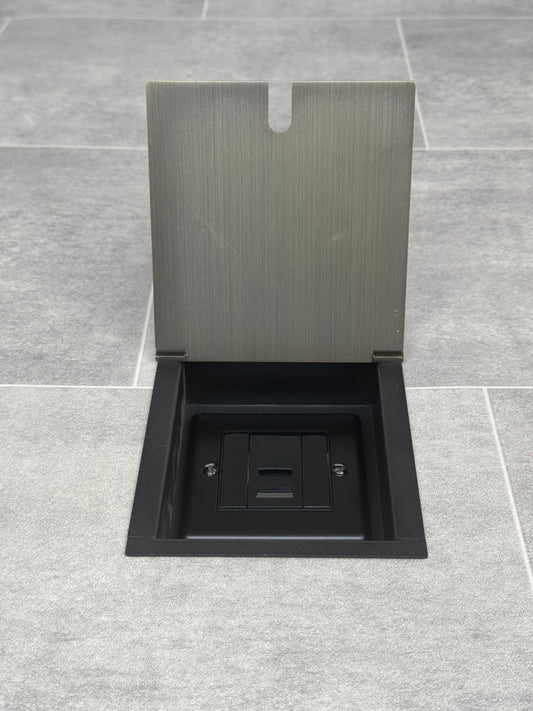 Antique brass recessed floor socket with lid open to show the single phone socket.