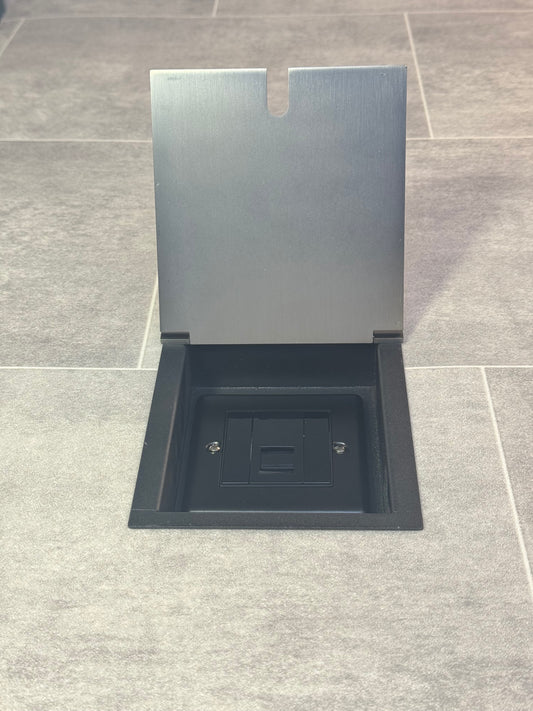 A UK telephone socket in an old bronze recessed floor socket.
