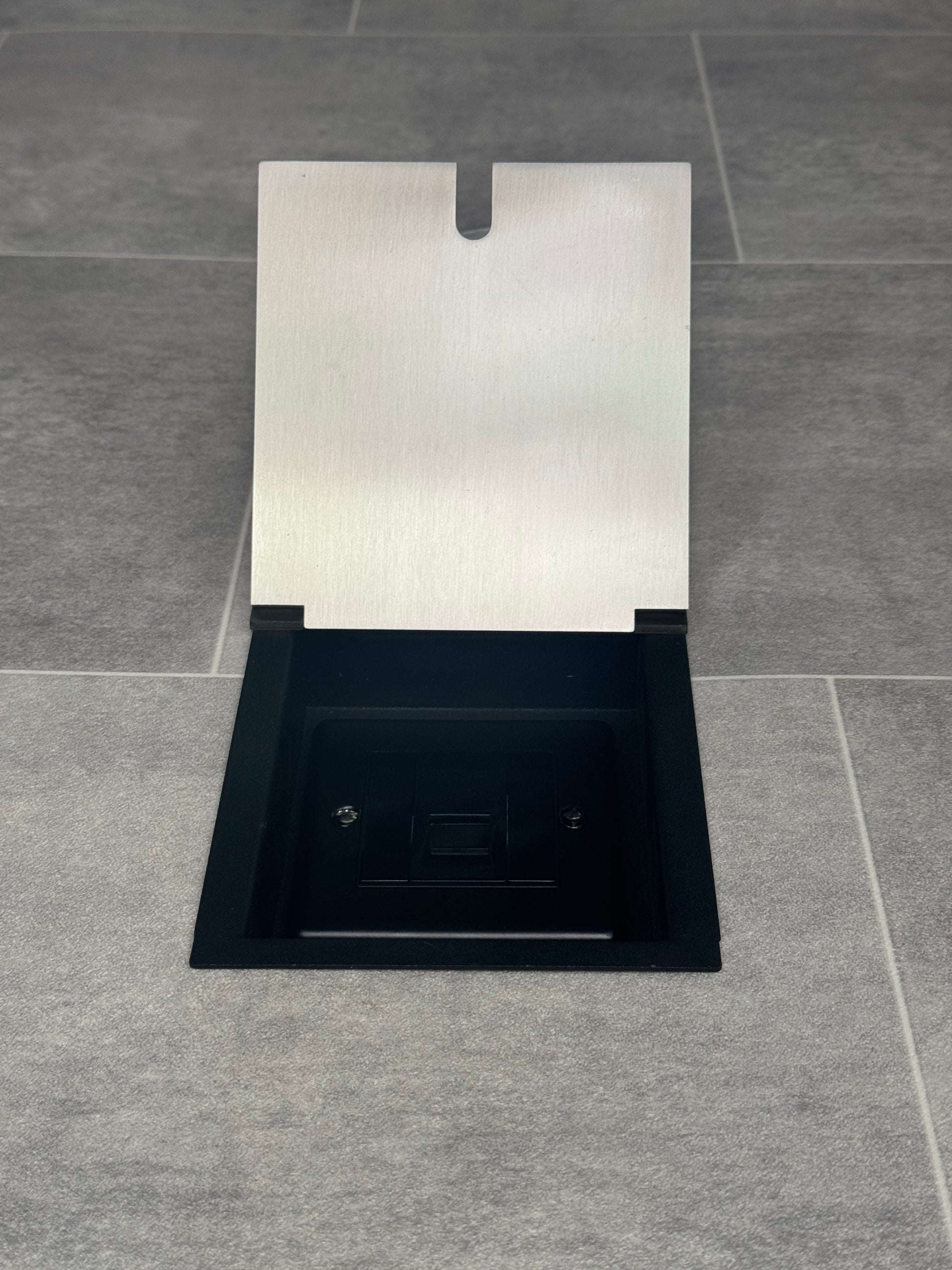 A satin stainless steel recessed floor socket with a single UK phone socket.
