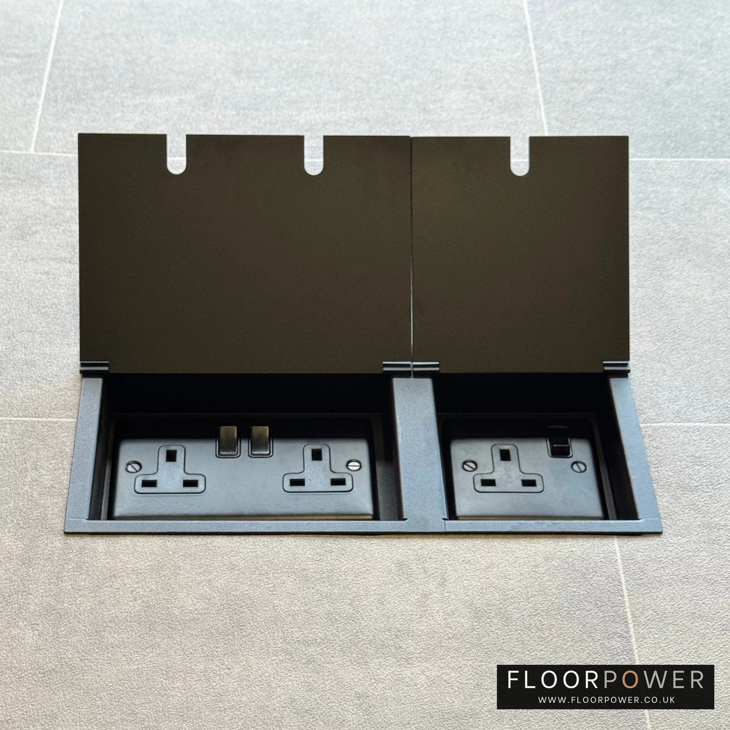 Matt Blackl triple floor plug socket with double 13A switched plug socket and a single 13A switched plug socket, both lids open.