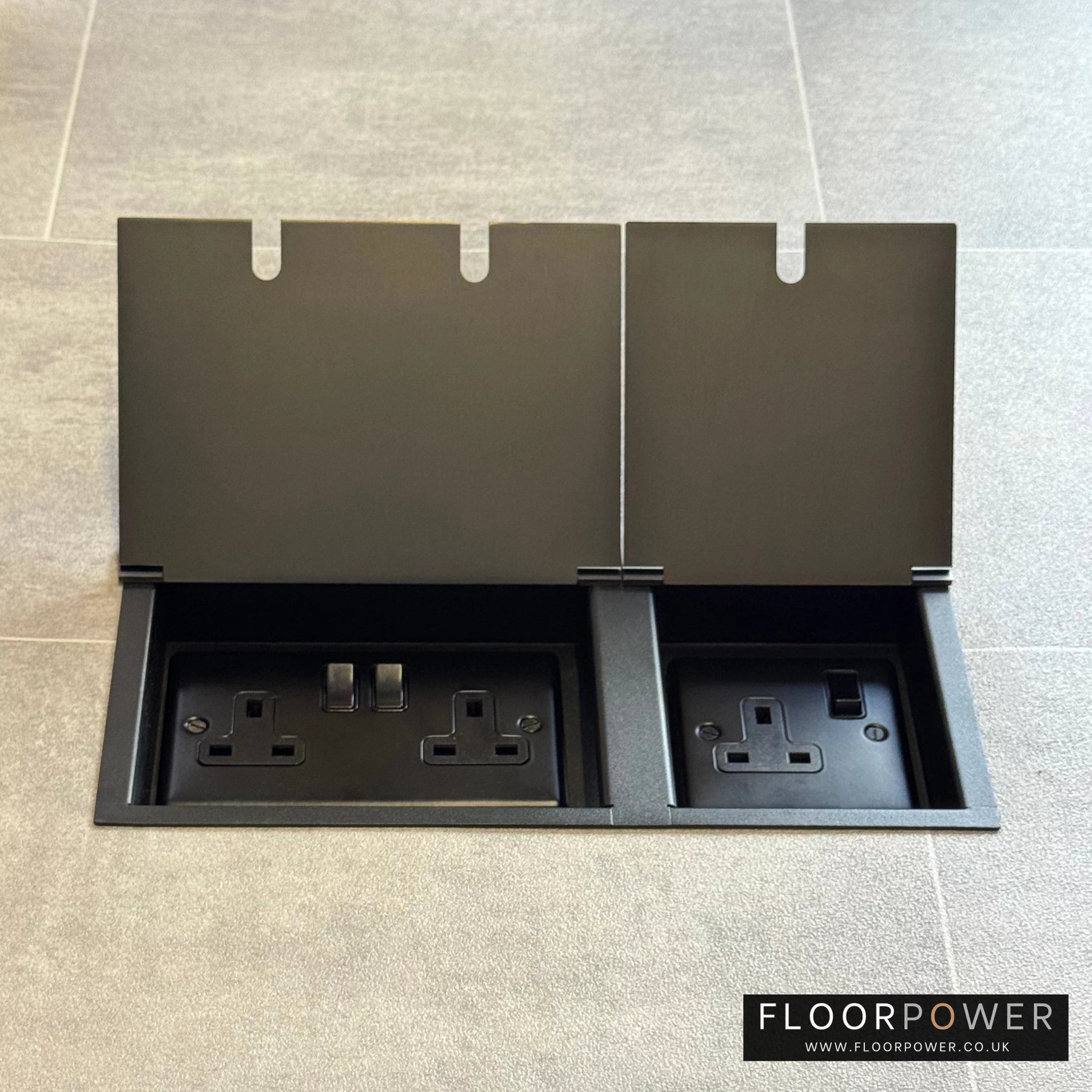 Old Bronze triple floor plug socket with double 13A switched plug socket and a single 13A switched plug socket, both lids open.