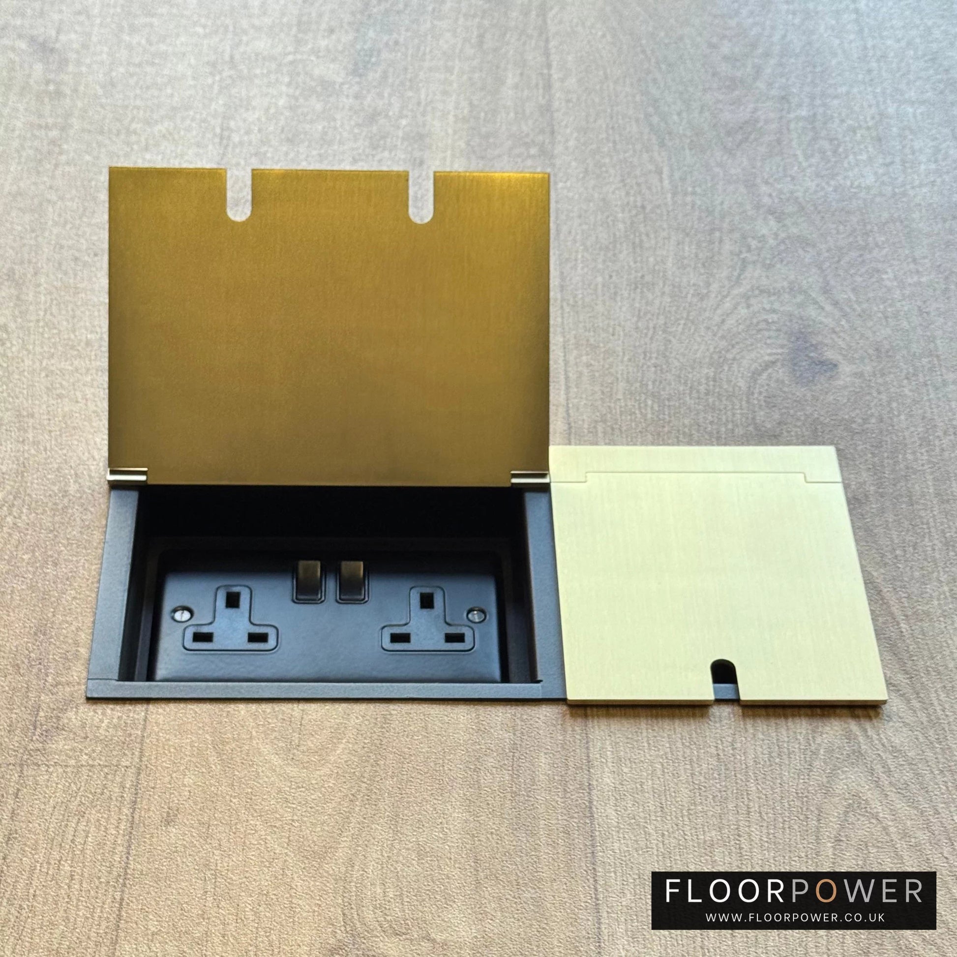 Triple Recessed Floor Socket in Satin Brass on a wood floor, with the double side lid open showing plug socket.