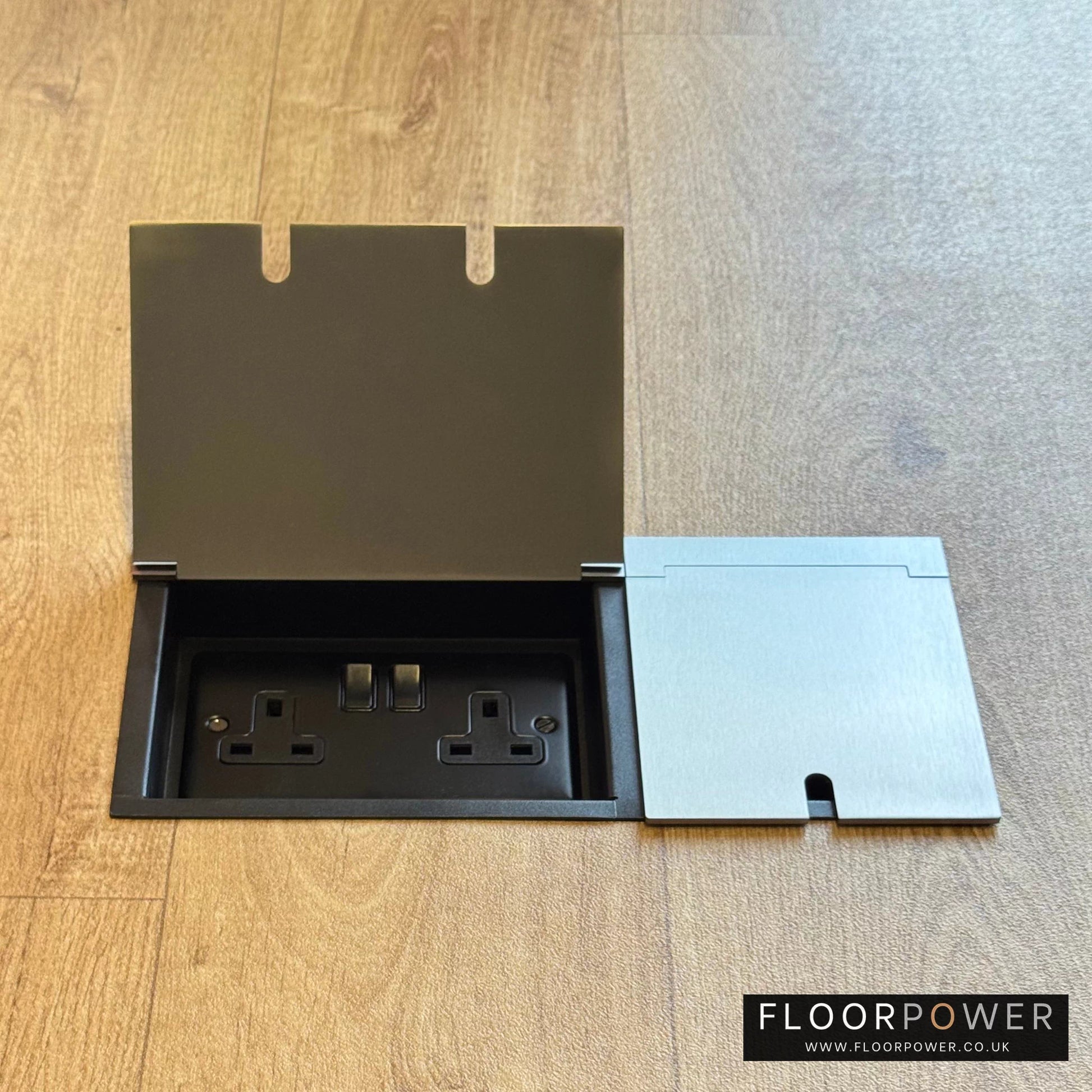 Triple Recessed Floor Socket in Satin Stainless on a wood floor, with the double side lid open showing plug socket.