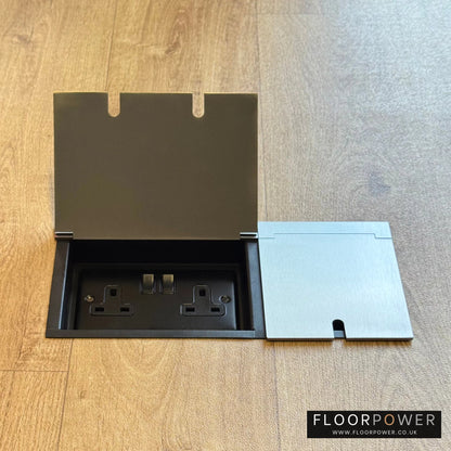 Triple Recessed Floor Socket in Satin Stainless on a wood floor, with the double side lid open showing plug socket.