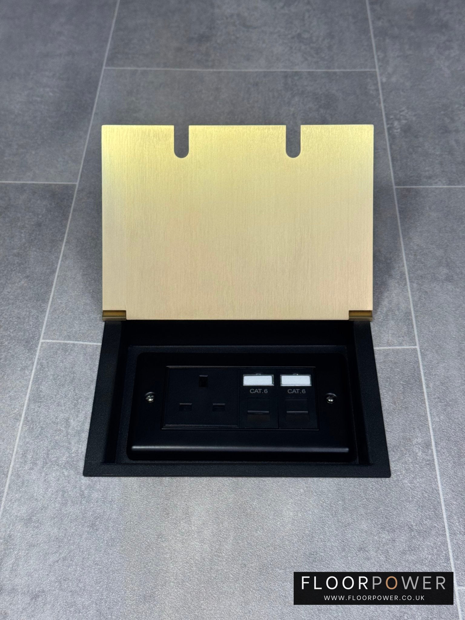 Double recessed floor socket in satin brass containing one 13amp unswitched socket and two RJ45 sockets in a tiled floor.