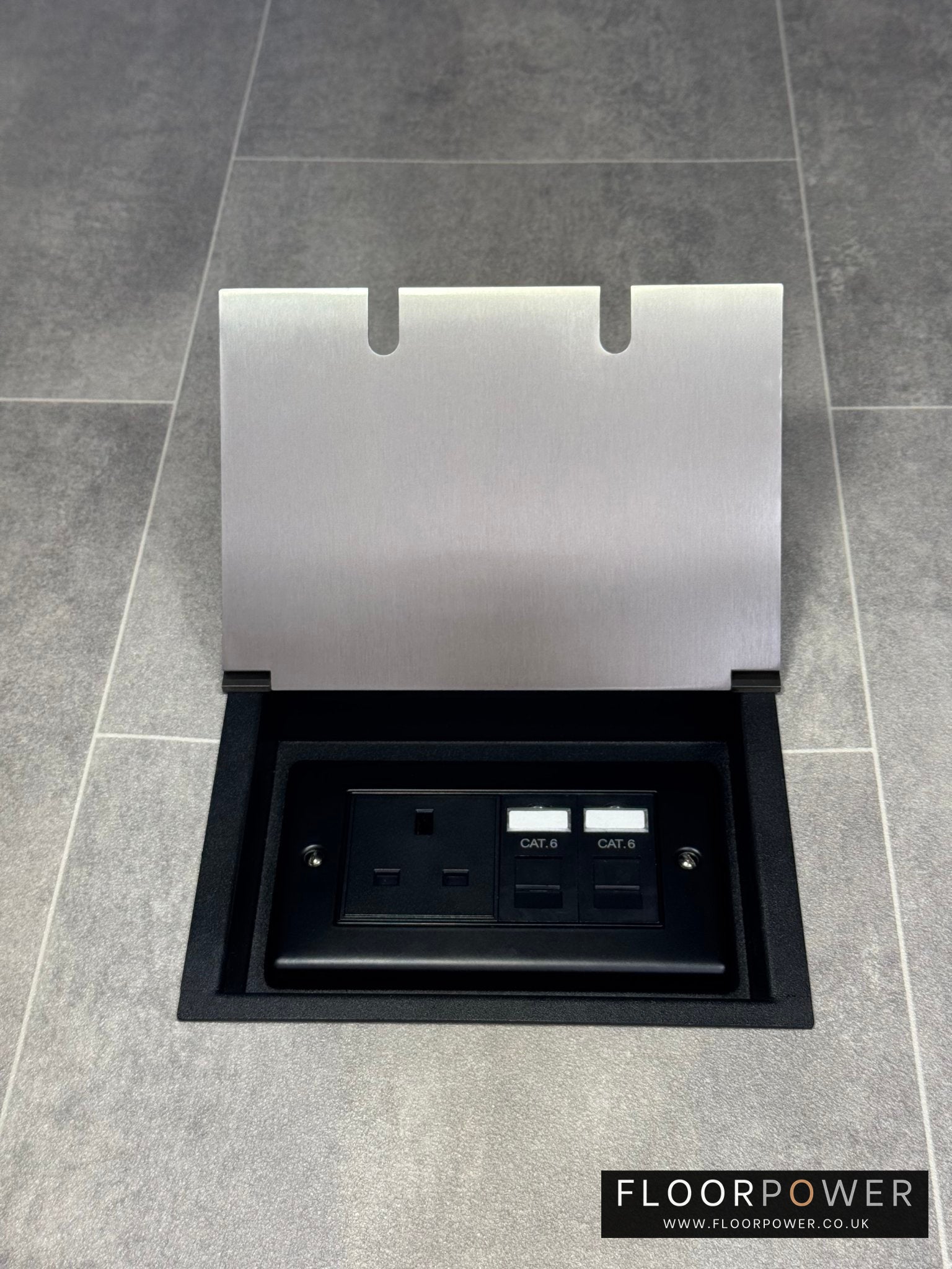A satin stainless steel double recessed floor socket with a 13amp unswitched socket and 2 RJ45 sockets, set in a gray tiled floor.